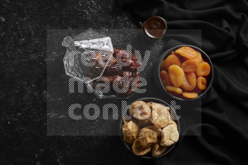 Dates in glass bowl with coffee and dried fruits in a dark setup