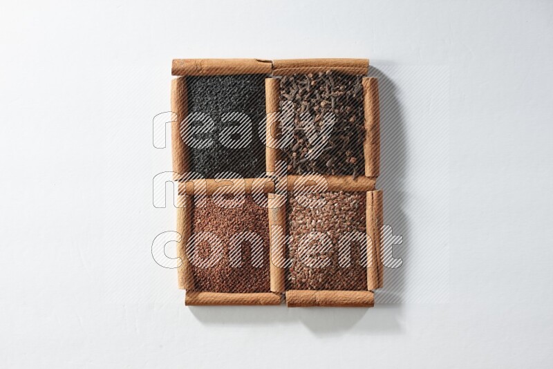 4 squares of cinnamon sticks full of black seeds, cloves, flaxseeds and garden cress on white flooring