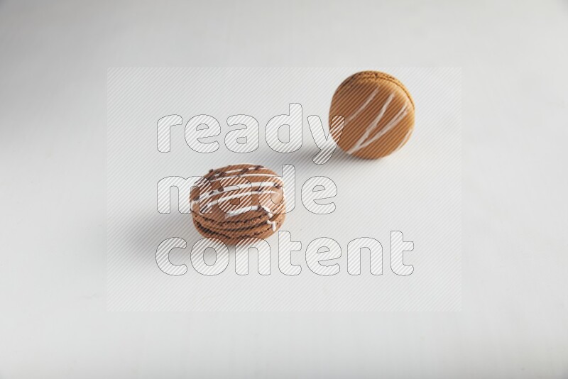 45º Shot of of two assorted Brown Irish Cream, and Brown white Chocolate Caramel macarons on white background