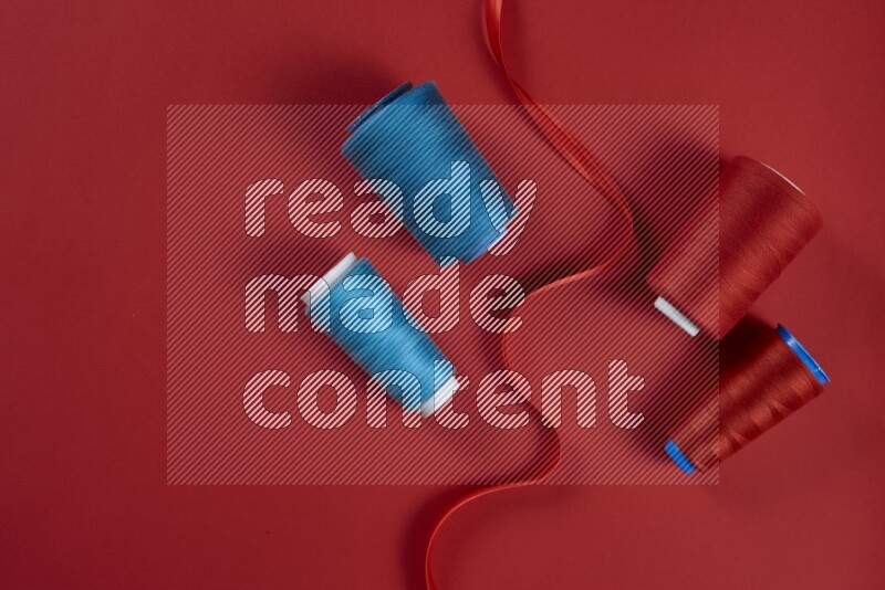 A blue and red collection of sewing and tailoring tools arranged on a red background