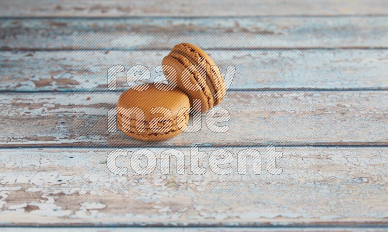 45º Shot of two Brown Maple Taffy macarons on light blue wooden background