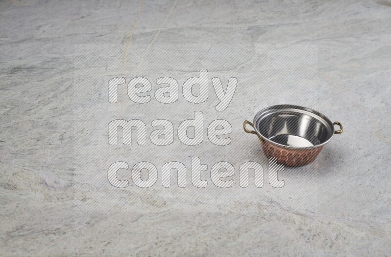 A small copper pot on grey marble background