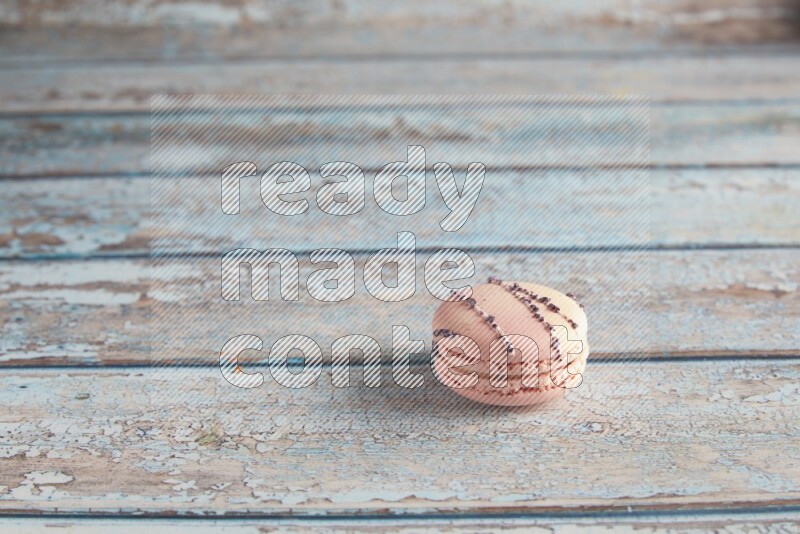 45º Shot of pink orange blossom macaron on light blue wooden background