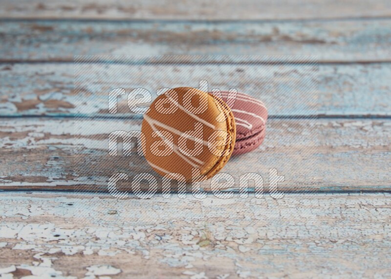 45º Shot of of two assorted Brown Irish Cream, and Red Poppy Flower macarons  on light blue background
