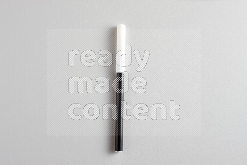 A close-up showing a single coloring pen with a cap on grey background