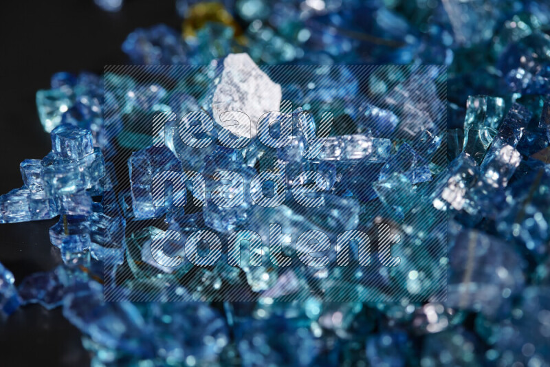 Transparent blue fragments of glass scattered on a black background