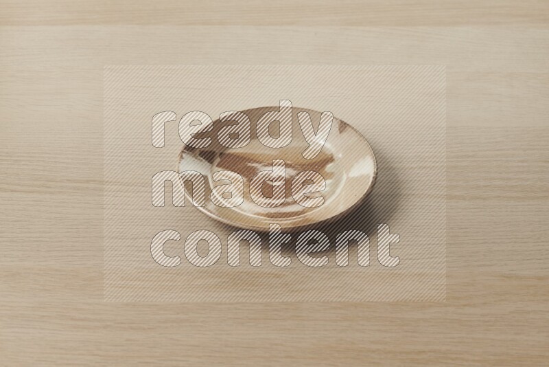 A multicolored pottery plate on light wooden background