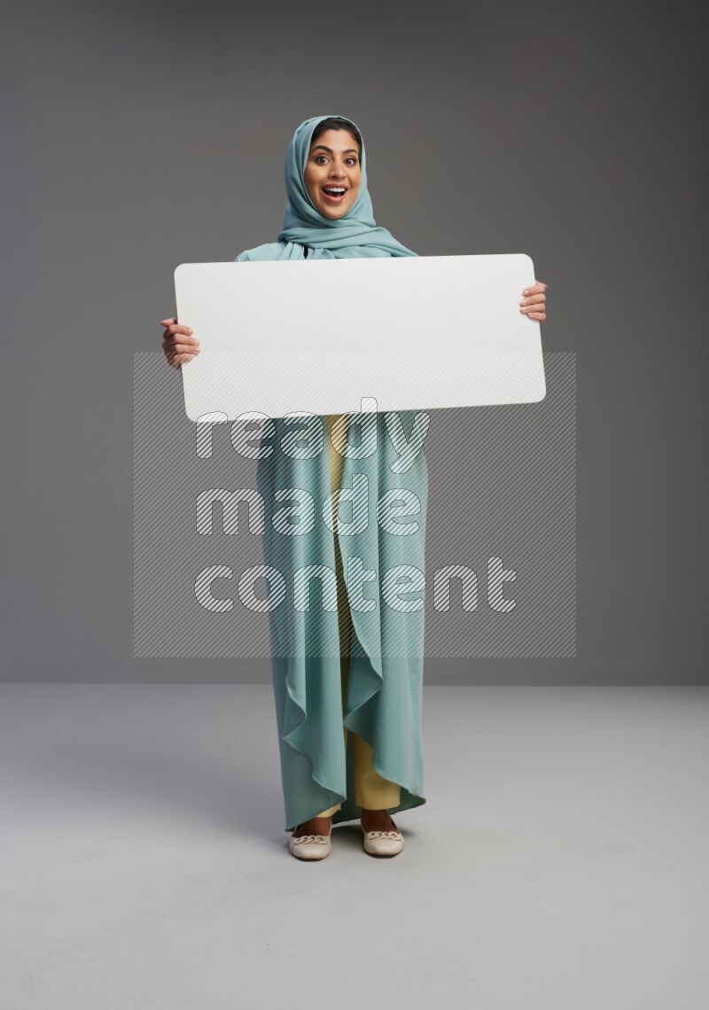 Saudi Woman wearing Abaya standing holding board on Gray background