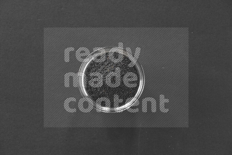 حبة البركة في وعاء زجاجي علي خلفية سوداء