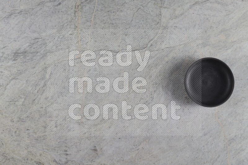 A black pottery bowl on grey marble background