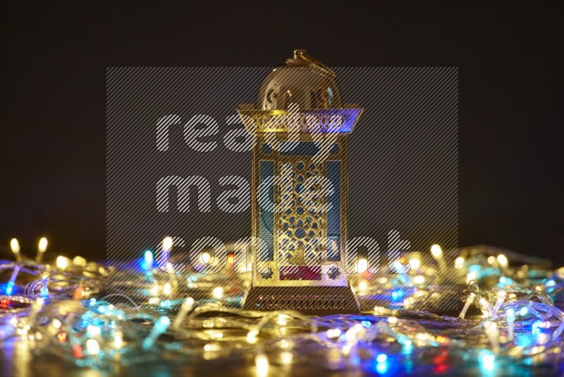 A traditional ramadan lantern surrounded by glowing fairy lights in a dark setup