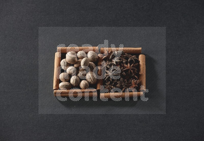 مربعان من أعواد القرفة ممتلئان بجوزة الطيب واليانسون النجمي علي خلفية سوداء