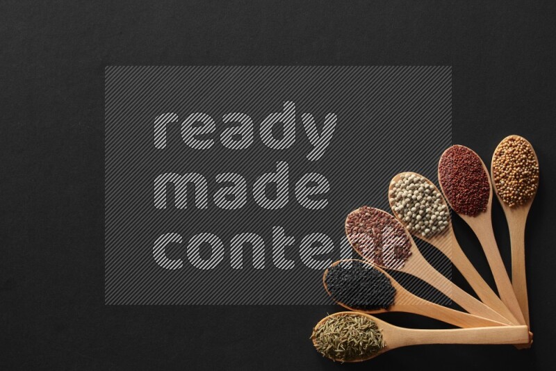 الفلفل الأسود وحبوب الخردل وحبة البركة وحب الرشاد والكمون و حبوب الكتان في معالق خشبية علي خلفية سوداء