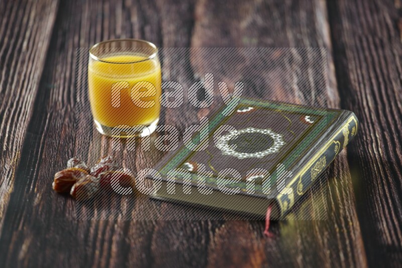 Quran with dates, prayer beads and different drinks all placed on wooden background
