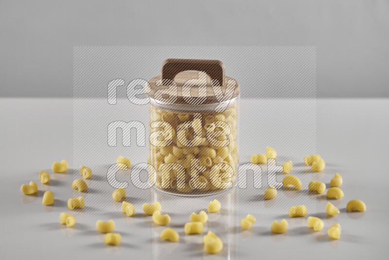 Raw pasta in a glass jar on light grey background