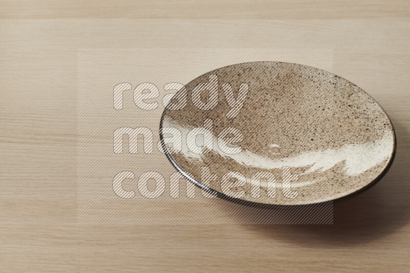 A beige pottery plate on light wooden background