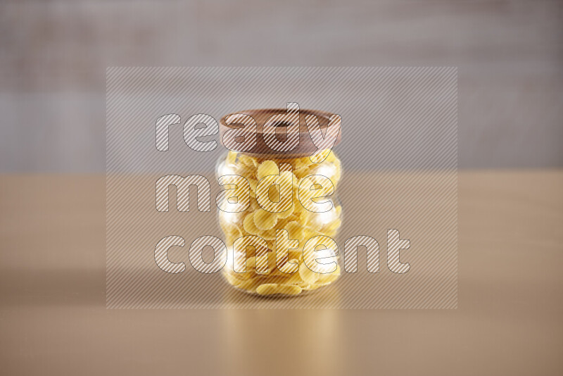 Raw pasta in glass jars on beige background