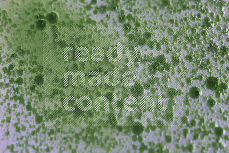 Close-ups of abstract green watercolor drops on oil Surface on white background