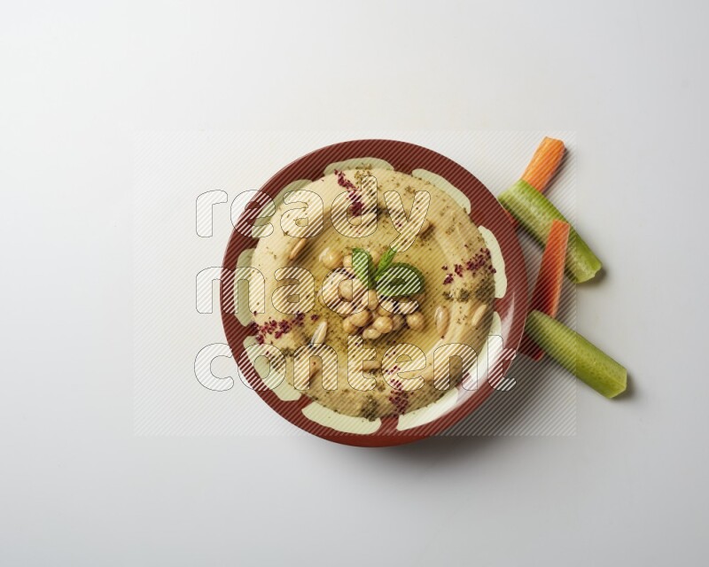 Hummus in a traditional plate garnished with zaatar & sumak on a white background