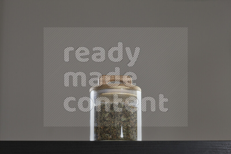 Dried basil in a glass jar on black background