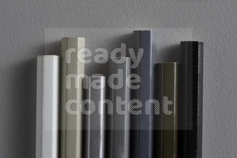 A collection of colored pencils arranged showcasing a gradient of white, grey and black hues on grey background