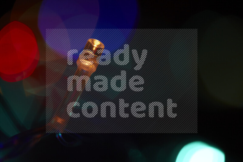 Light bulbs glowing against backdrop of multicolord bokeh