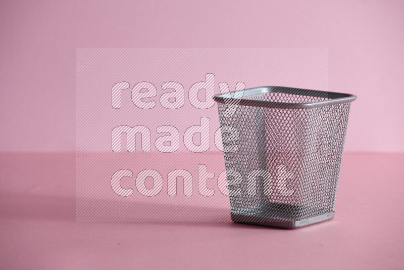 Pens, pencils and other different school supplies in a metal pen holder on rose background