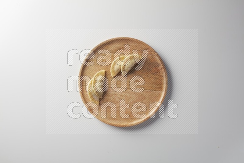 Four Sambosas on a wooden round plate on a white background