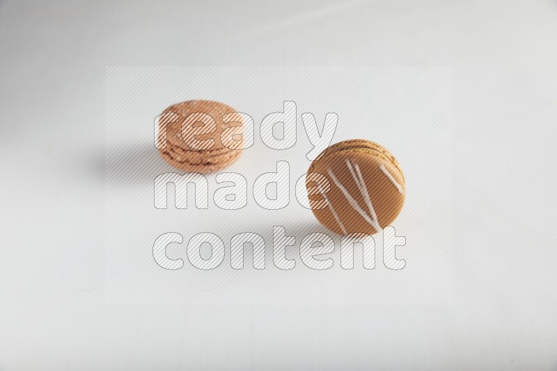 45º Shot of of two assorted Brown Irish Cream, and Brown Hazelnuts macarons on white background