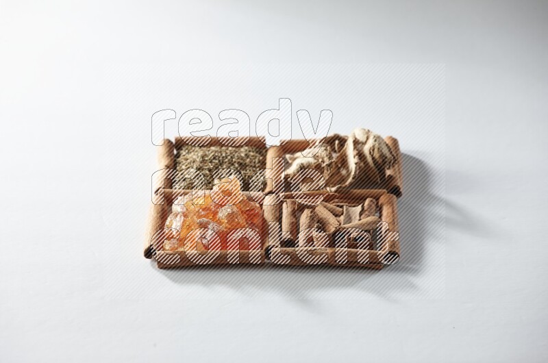 4 مربعات من أعواد القرفة ممتلئة بالكمون والقرفة والزنجبيل المجفف والصمغ العربي على أرضية بيضاء