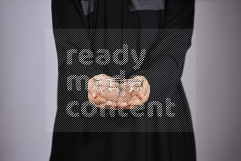 A woman in black abaya holding different glassware in different positions