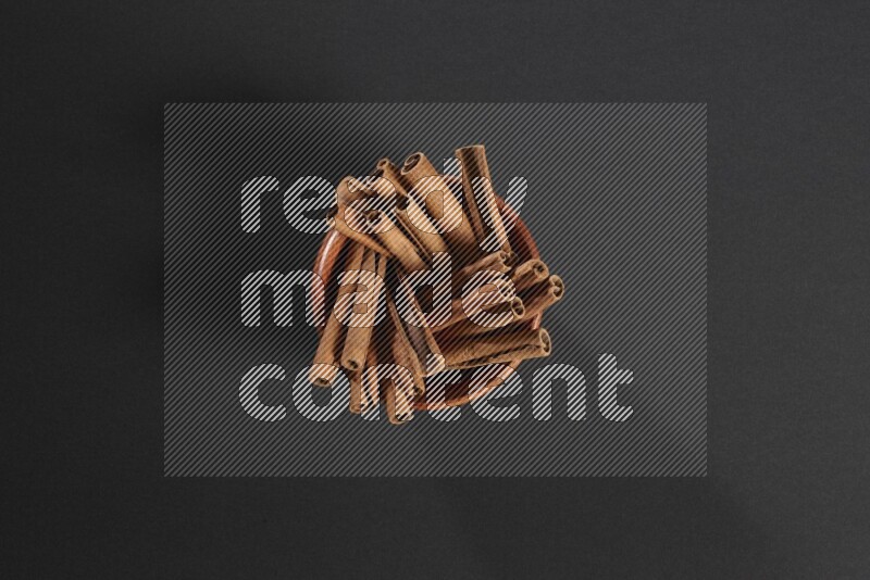 Cinnamon Sticks in a wooden bowl on black background
