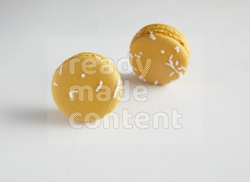 45º Shot of two Yellow Piña Colada macarons on white background