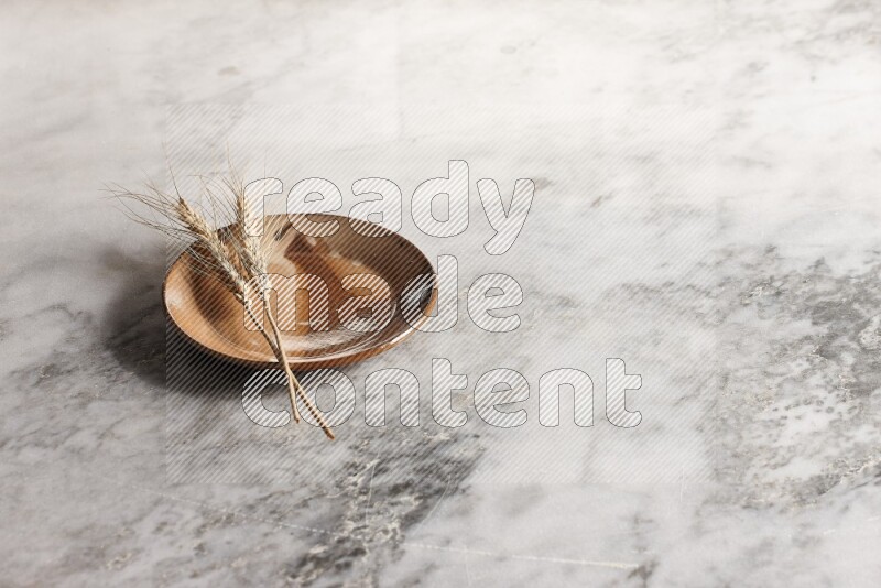 Wheat stalks on multicolored pottery plate on grey marble background
