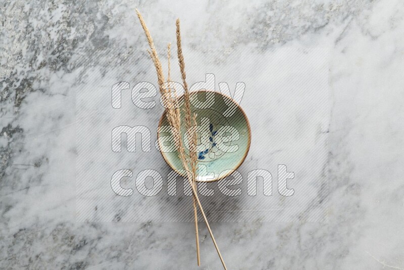 Wheat stalks on decorative pottery plate on grey marble background