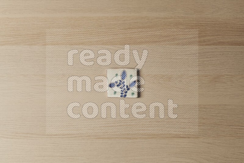 A decorative pottery coaster on light wooden background