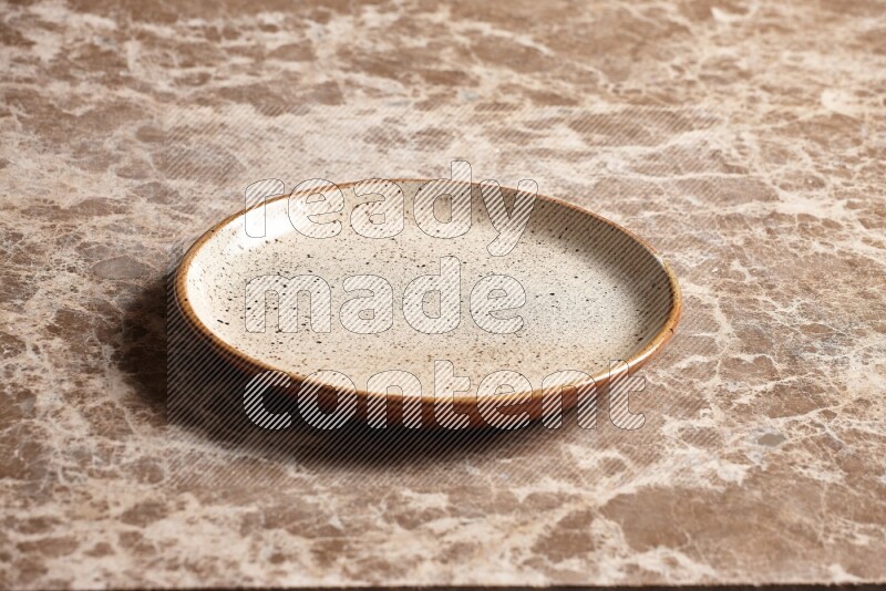 A multicolored pottery plate on beige marble background