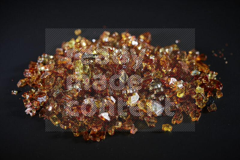 Transparent orange fragments of glass scattered on a black background