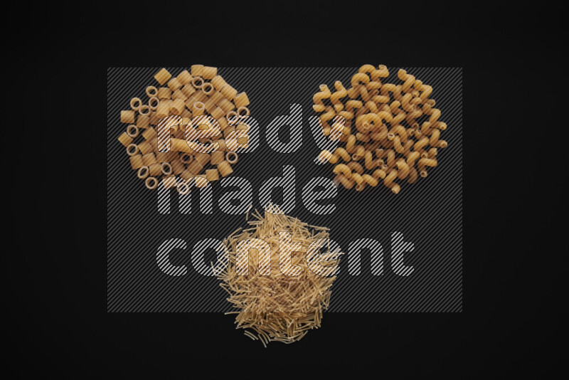 Different pasta types in bunches on black background