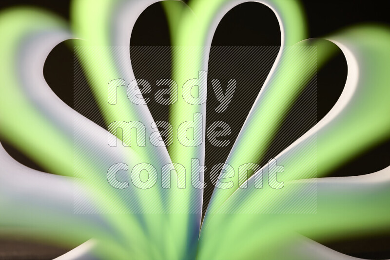 An abstract art piece displaying smooth curves in white and green gradients created by colored light
