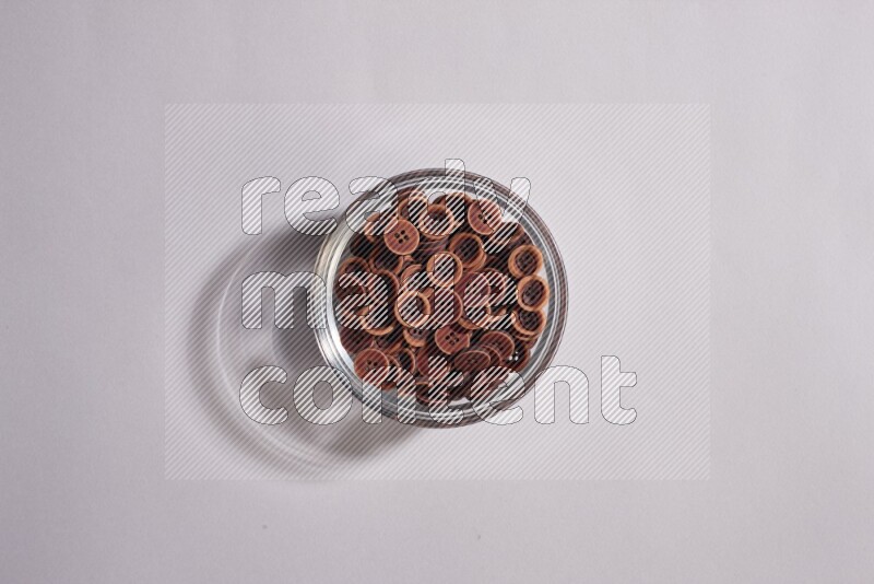 Colored buttons in a glass bowl on grey background
