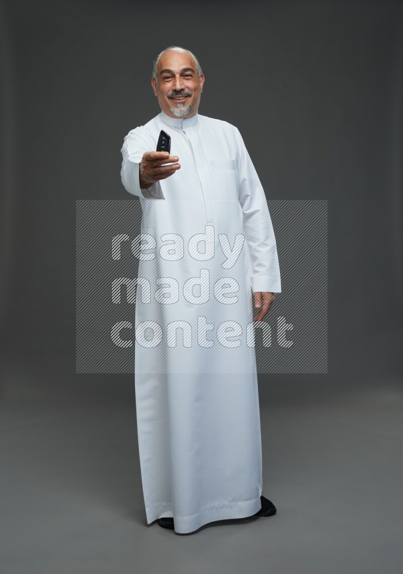 Saudi man without shomag Standing holding car key on gray background