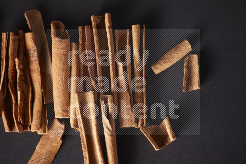 Cracked cinnamon sticks on a black background