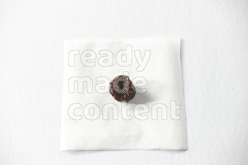 A dried plum on a piece of paper on a white background in different angles