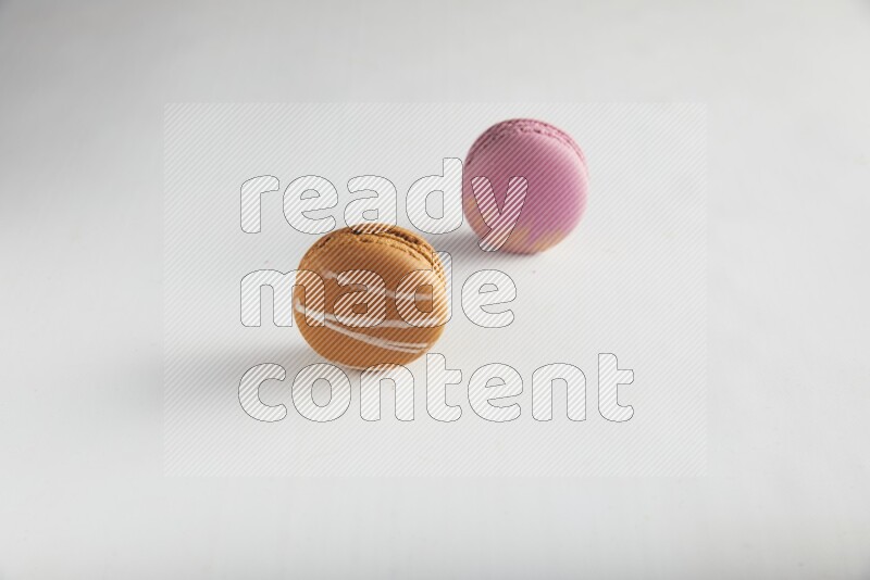 45º Shot of of two assorted Brown Irish Cream, and Purple Strawberry macarons on white background