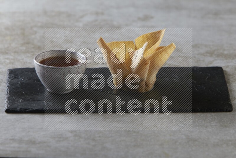 wonton cups with soy sauce ramkin on rectangle slate on grey textured counter top