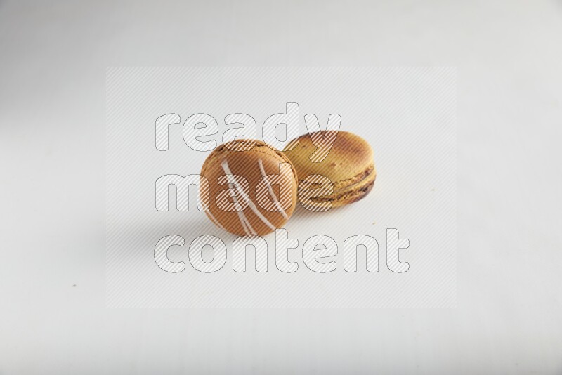 45º Shot of of two assorted Brown Irish Cream, and Yellow Crème Brulée macarons on white background