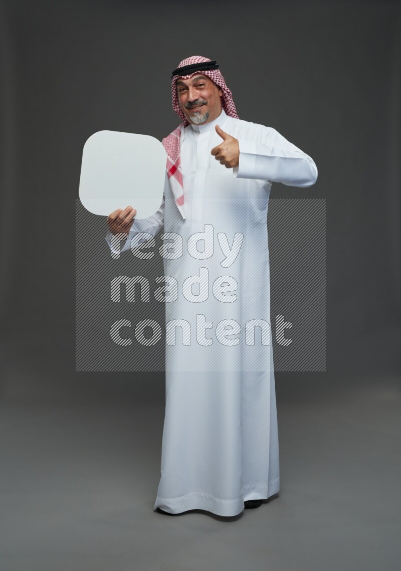 Saudi man with shomag Standing holding social media sing on gray background