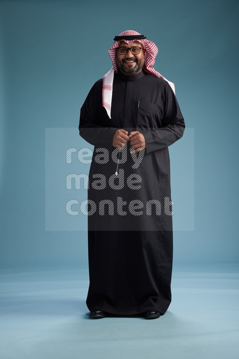 Saudi Man with shimag Standing Interacting with the camera on blue background