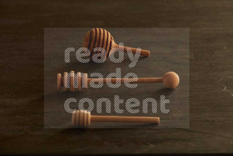 Wooden honey dipper on black slate background